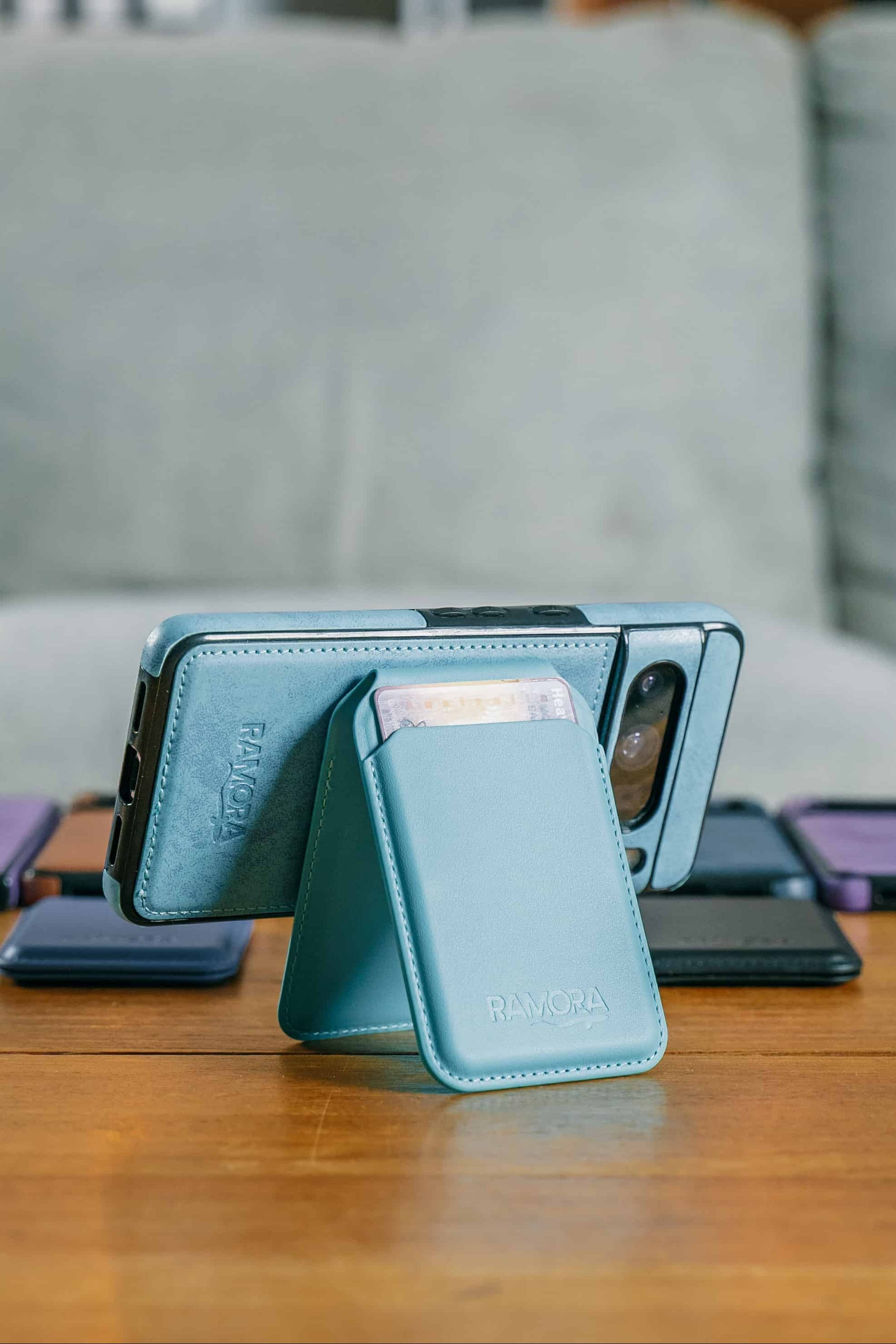 Blue phone case with stand on a wooden table with multiple phones in the background.