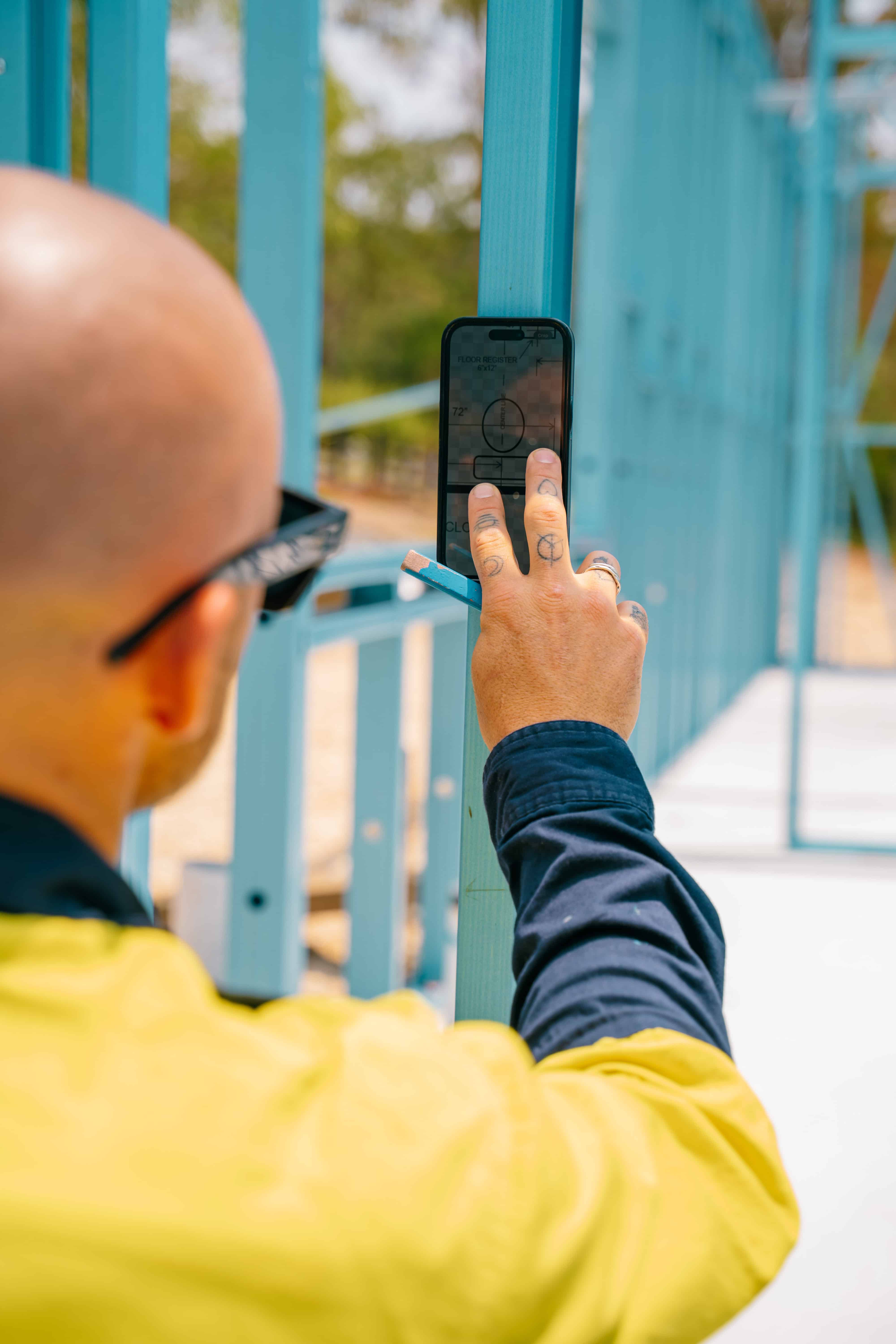 Person taking a photo with a smartphone in front of a blue metal structure
